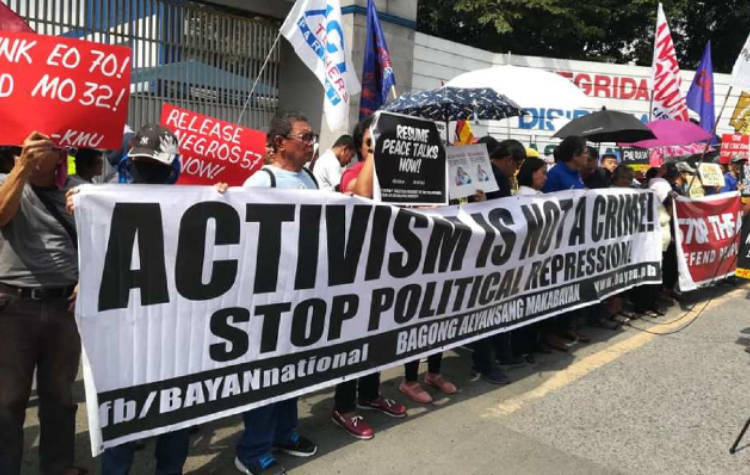 Activists protesting on ground, saying, 'Activism is not a crime. Stop political oppression'